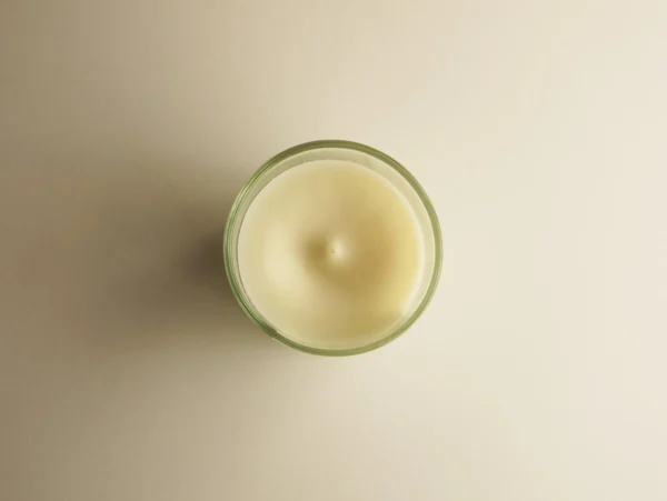 Vue de dessus d'une bougie artisanale coulée dans un contenant en verre, réalisée avec des huiles essentielles naturelles au parfum de cèdre et bois de oud